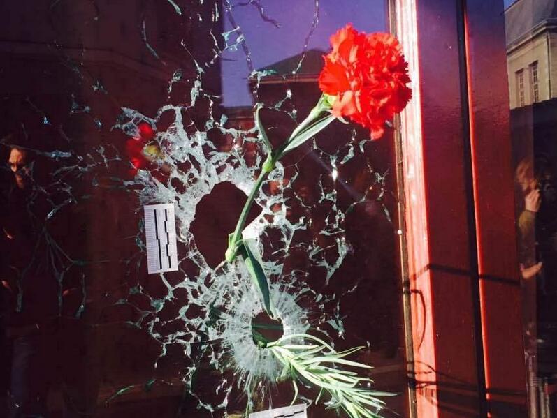 フランスパリで襲撃されたバーで、窓の弾痕に生花を